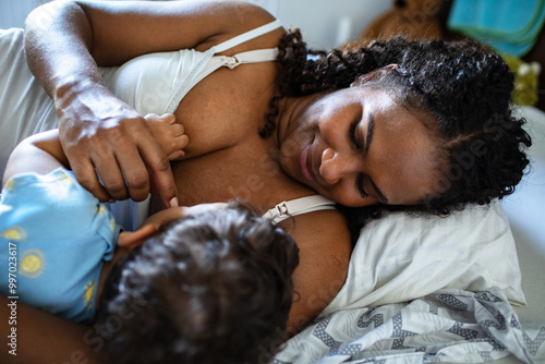 Mother holding infant son in the bedroom at home photo