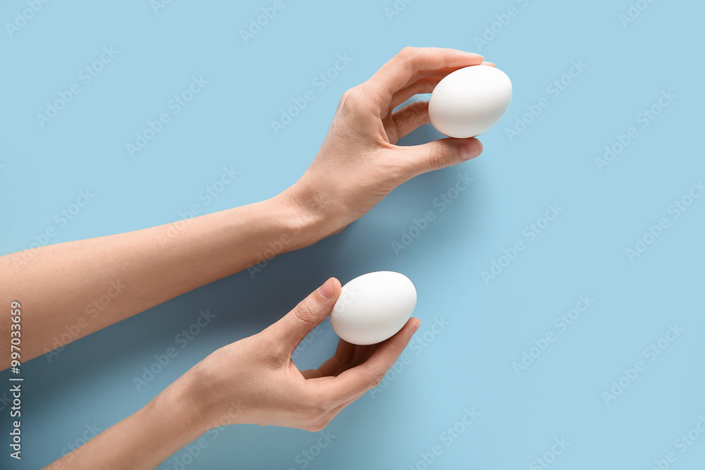 Female hands with raw chicken eggs on blue background Female hands with raw chicken eggs on blue background