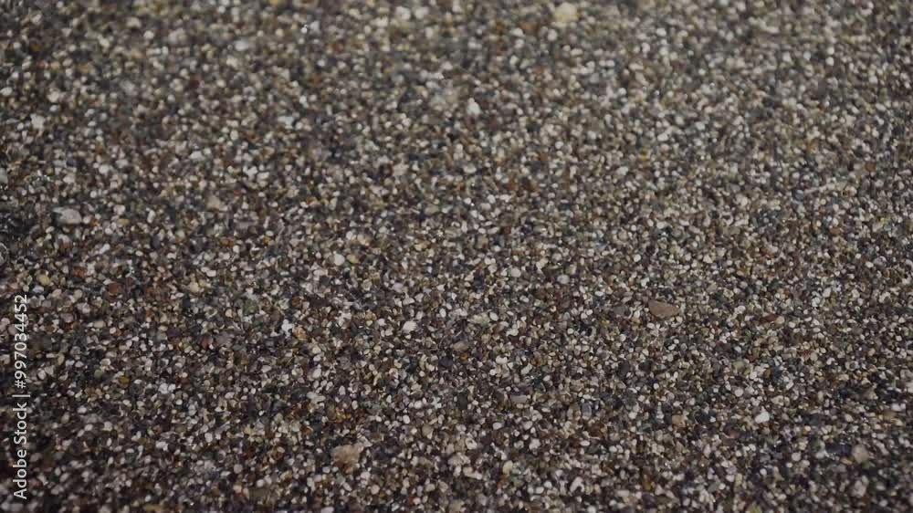 Clear water sea waves rolling on small crushed stone beach. Top view on ocean tides coming on brown pebble coast. Calm, relax, summertime vacations concept. High quality 4k footage Clear water sea waves rolling on small crushed stone beach. Top view on ocean tides coming on brown pebble coast. Calm, relax, summertime vacations concept. High quality 4k footage