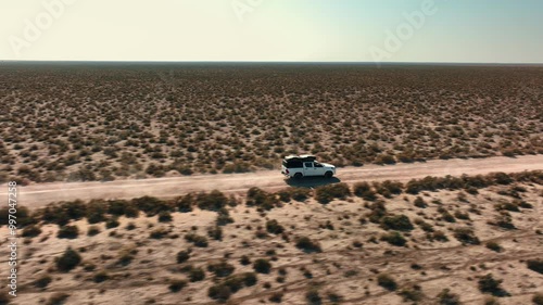 White pick up four by four carrying equipment, driving on the sand of the Namib desert .