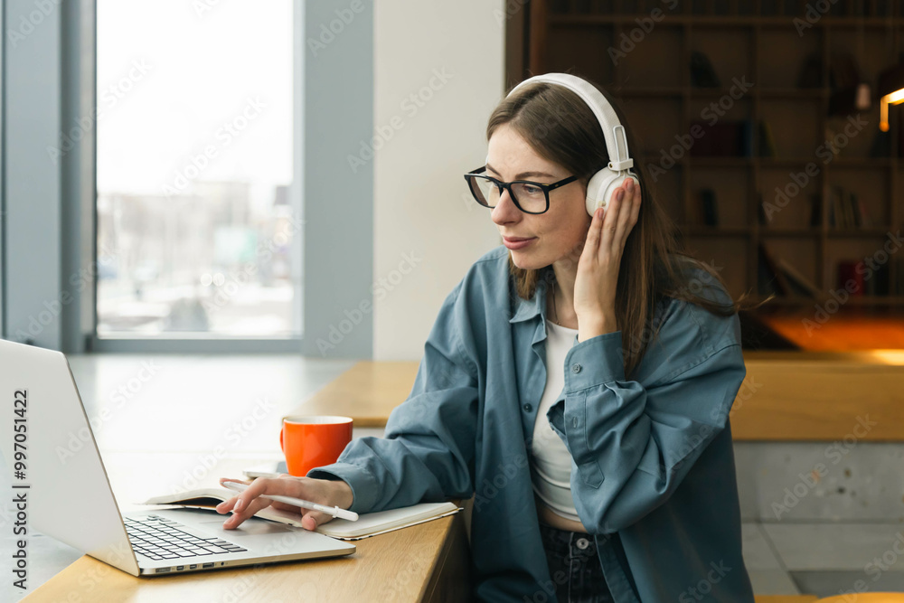 Portrait of smiling woman sitting at desk, using laptop and writing in notebook. Portrait of smiling woman sitting at desk, using laptop and writing in notebook.