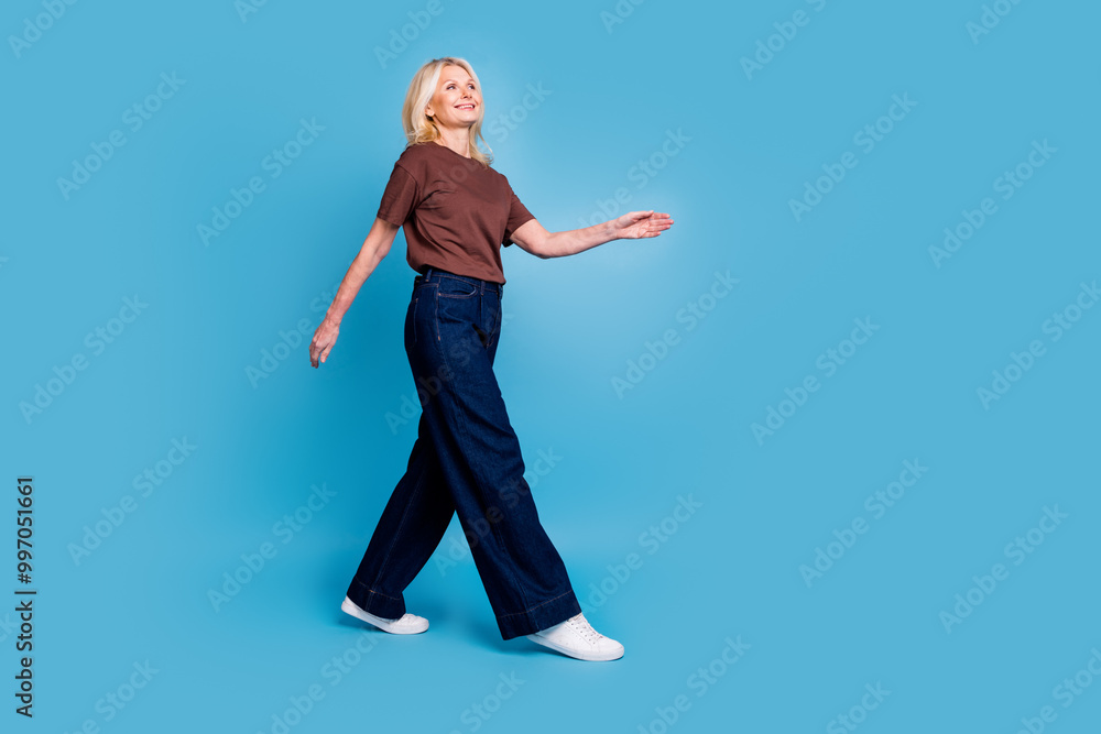 Photo of adorable lovely woman pensioner wear brown clothes go empty space isolated on blue color background Photo of adorable lovely woman pensioner wear brown clothes go empty space isolated on blue color background