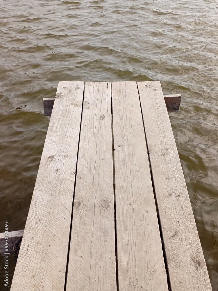 Fototapeta premium Vertical photo of a wooden old pier above the surface of a lake.