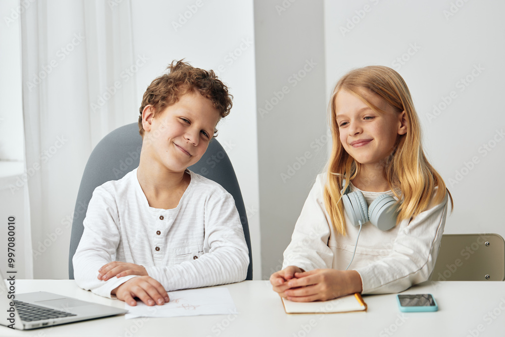 Boy and girl happily studying together at home, using laptops and headphones for online education The siblings are sitting at a table in their cozy living room, immersed in their elearning lessons Boy and girl happily studying together at home, using laptops and headphones for online education The siblings are sitting at a table in their cozy living room, immersed in their elearning lessons
