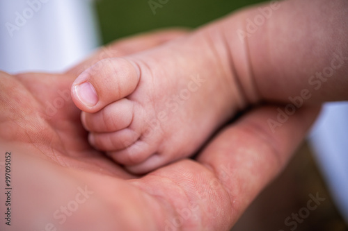 leg of newborn baby held by parents, baby, close-up view, selective focus