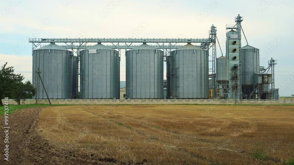 silver silos on agro manufacturing plant for processing drying cleaning and storage of agricultural products, flour, cereals and grain. Large iron barrels of grain. Granary elevator silver silos on agro manufacturing plant for processing drying cleaning and storage of agricultural products, flour, cereals and grain. Large iron barrels of grain. Granary elevator