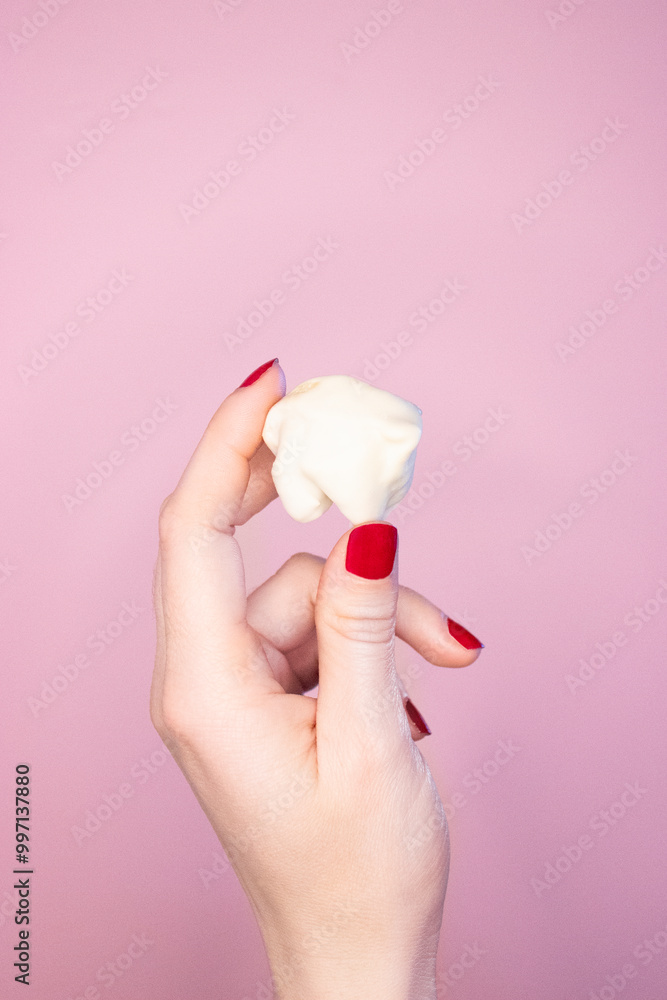 female hand holding a cookie dipped in white chocolate female hand holding a cookie dipped in white chocolate