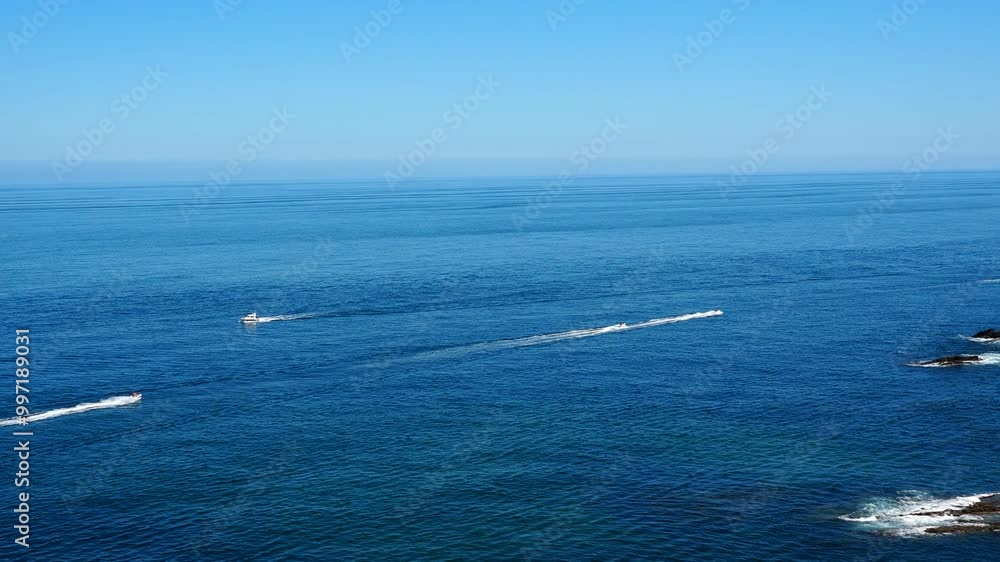 Boats sail across the endless ocean and leave a white trail. Blue sky and ocean merge. Endless water. Tour, boat excursion Boats sail across the endless ocean and leave a white trail. Blue sky and ocean merge. Endless water. Tour, boat excursion