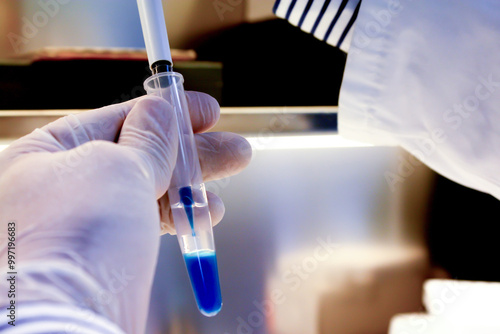 Scientist working in laboratory; Pipette dropping sample into test tube. Laboratory glassware, science laboratory research concept.