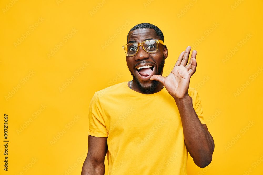 Happy young man expressing excitement in bright yellow shirt against a vibrant yellow background, wearing glasses and gesturing enthusiastically with a joyful smile Happy young man expressing excitement in bright yellow shirt against a vibrant yellow background, wearing glasses and gesturing enthusiastically with a joyful smile