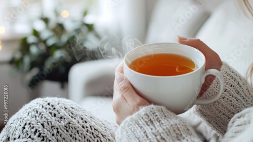 Closeup of woman's hands holding a steaming cup of tea.