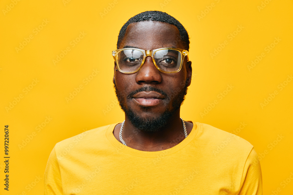 Portrait of a stylish man with glasses, wearing a yellow shirt, exhibiting confidence and warmth against a vibrant yellow background, highlighting modern fashion trends Portrait of a stylish man with glasses, wearing a yellow shirt, exhibiting confidence and warmth against a vibrant yellow background, highlighting modern fashion trends