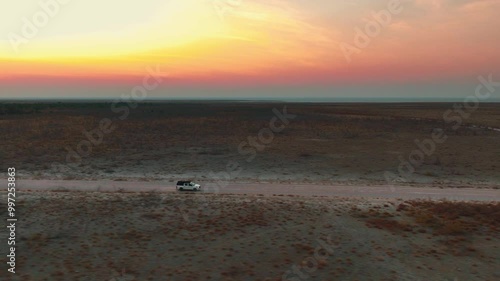 White pick up four by four carrying equipment, driving on the sand of the Namib desert .