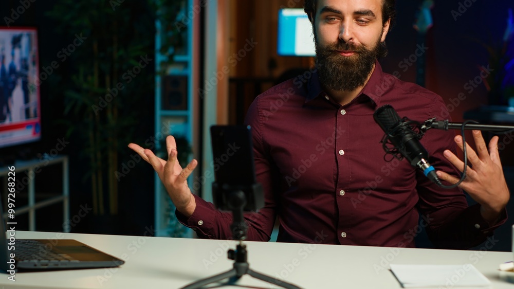 Influencer talks in front on smartphone attached to tripod and high quality mic in studio, discussing with viewers. Man using mobile phone and professional gear to record social media video, camera A Influencer talks in front on smartphone attached to tripod and high quality mic in studio, discussing with viewers. Man using mobile phone and professional gear to record social media video, camera A