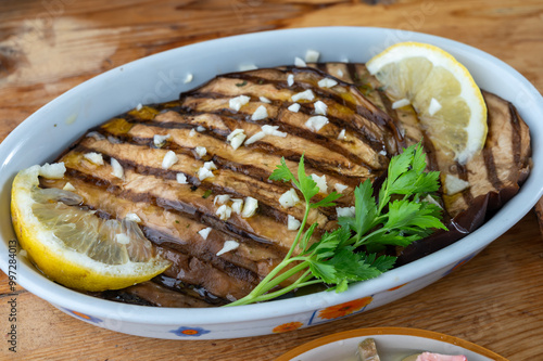 Italian style starter served in restaurant, grilled eggplant with garlic, olive oil and fresh parsley photo