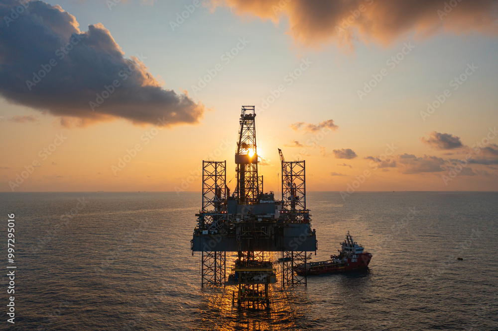 Aerial view of silhouette offshore jack up drilling rig during sunset - oil and gas industry. Aerial view of silhouette offshore jack up drilling rig during sunset - oil and gas industry.