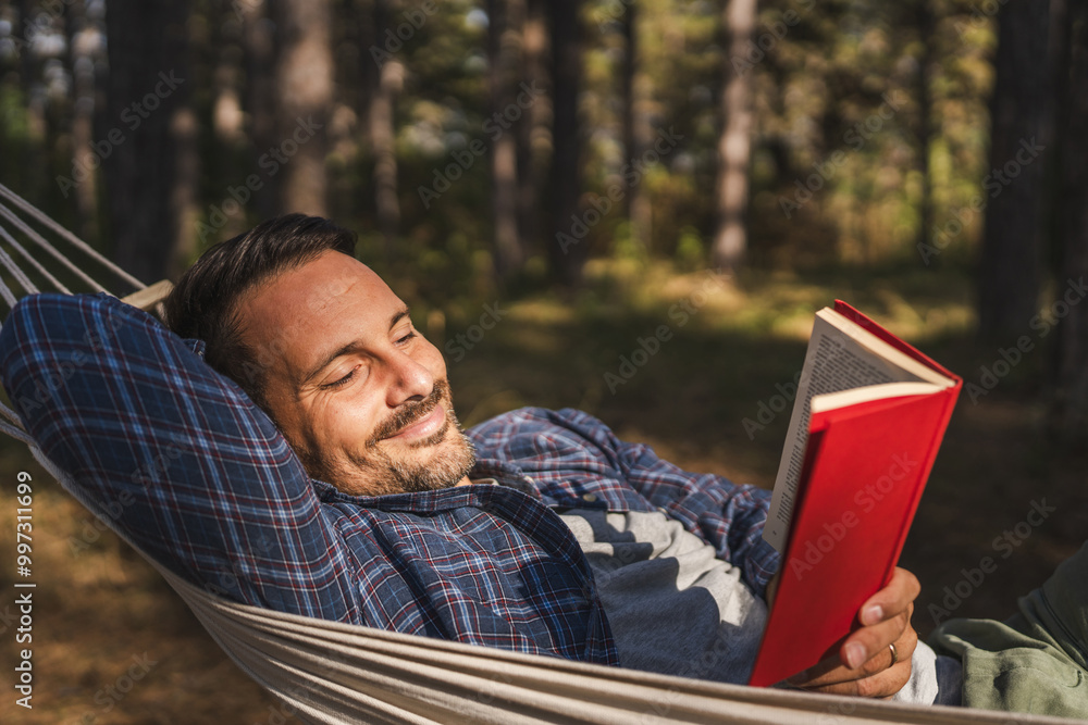Adult man lying down and read book in hammock Adult man lying down and read book in hammock