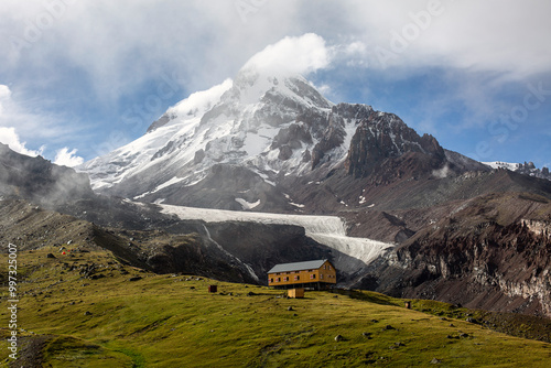 A dramatic mountain scene with a river cutting through a valley, leading to a snow-covered peak.