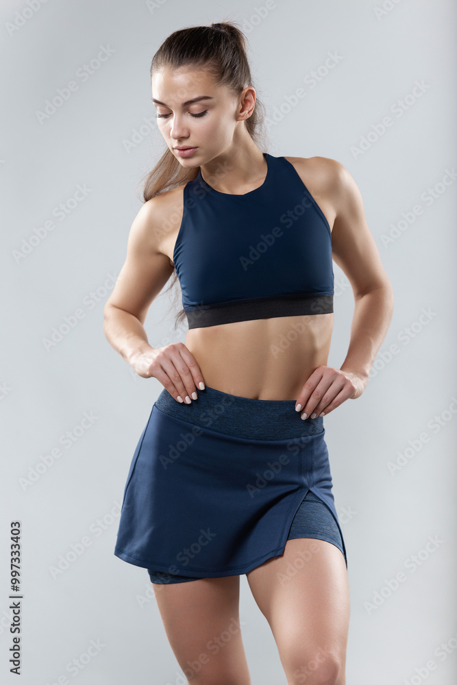 Young attractive girl in fitness clothes on a gray studio background. Young attractive girl in fitness clothes on a gray studio background.