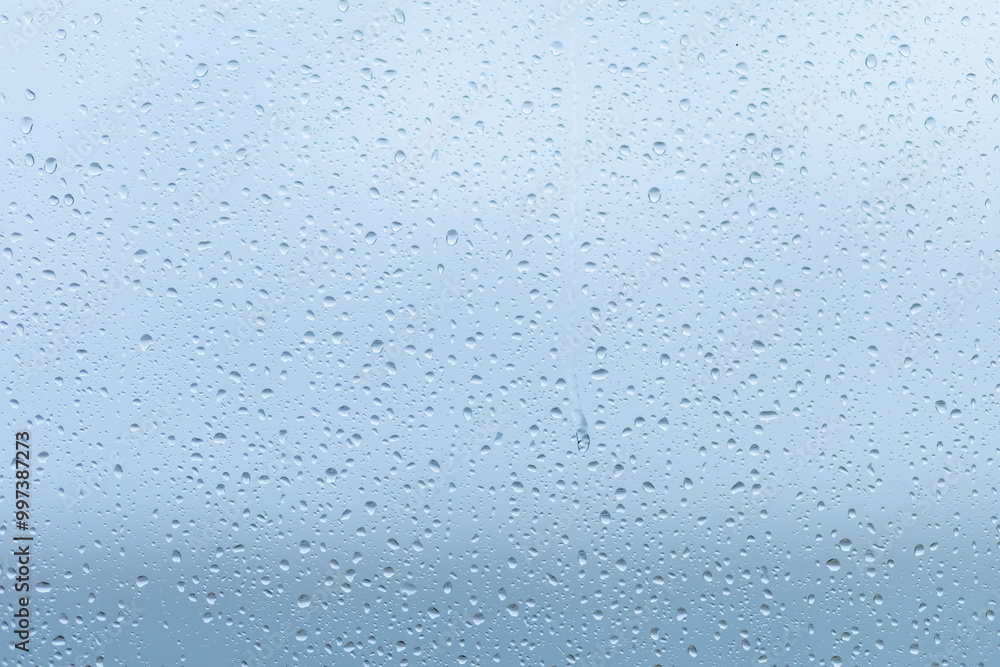 Raindrops forming a delicate pattern on a window pane, blurring the outside view during a cloudy afternoon in early fall Raindrops forming a delicate pattern on a window pane, blurring the outside view during a cloudy afternoon in early fall