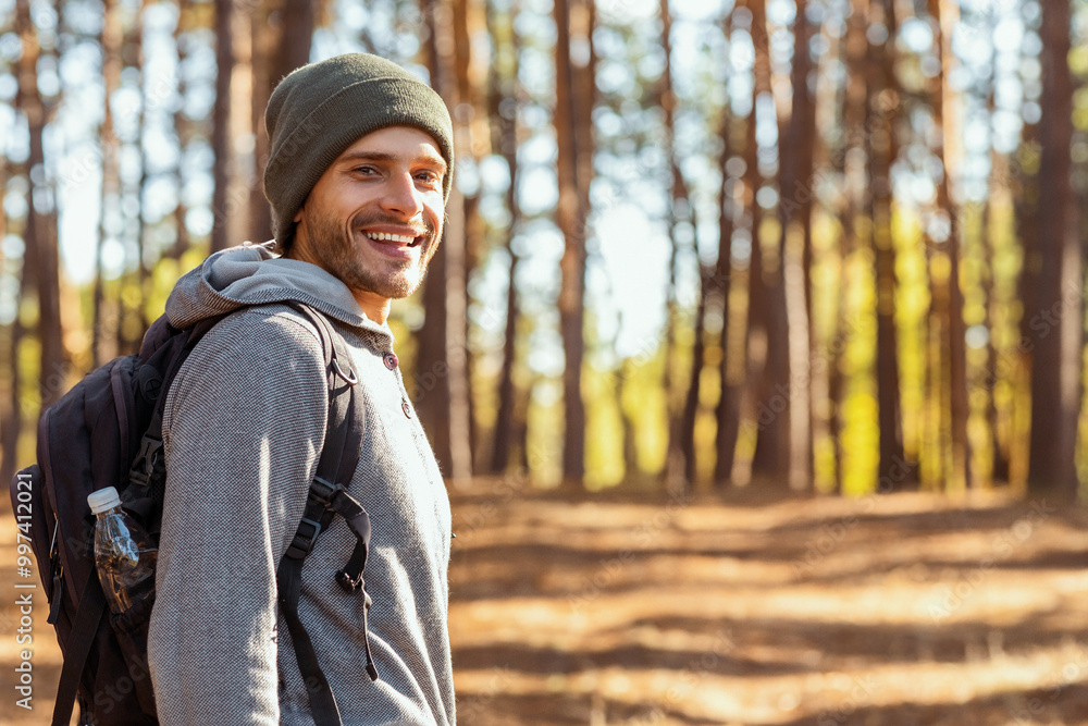 Smiling young man backpacker hiking with friends at forest, looking at camera, back view Smiling young man backpacker hiking with friends at forest, looking at camera, back view