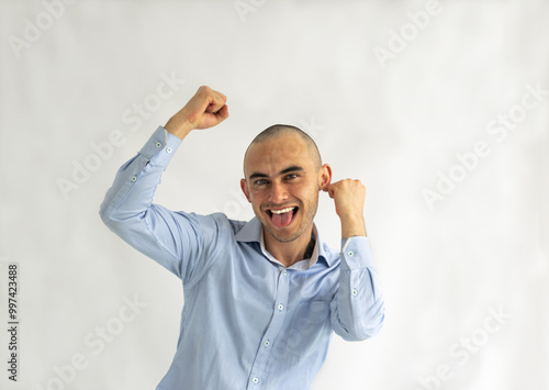 Shaved young man with a big smile rejoicing ecstatically with raised fists photo