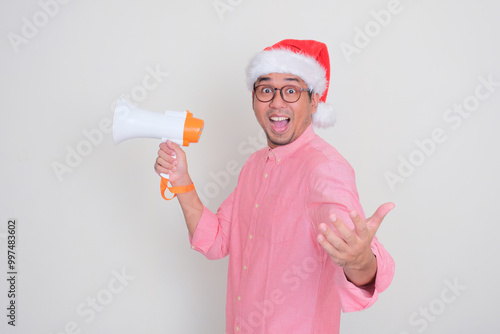 A man wearing santa hat holding megaphone showing wow face expression photo