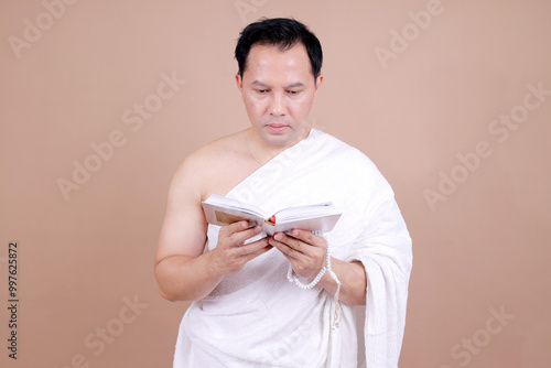 Religious Muslim Man Reading Al Quran Isolated Beige Background
 photo