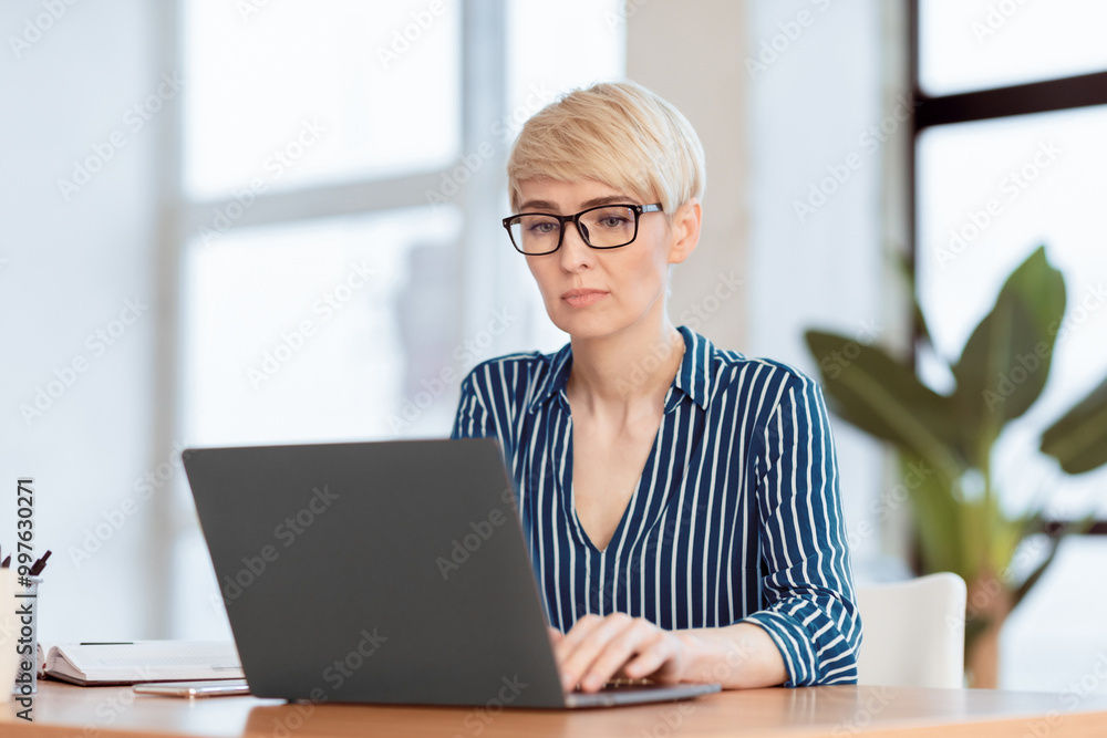 Serious Middle-Aged Businesswoman Using Laptop Working Sitting In Modern Office. Selective Focus