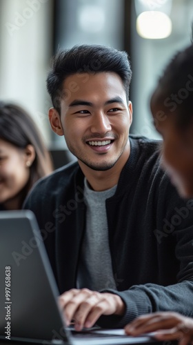 Young asian male teacher and diverse students gather around a laptop in the classroom