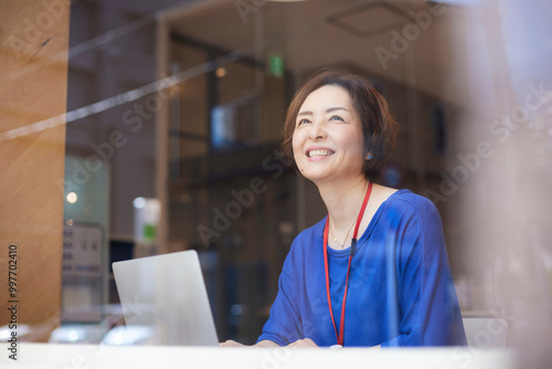 オフィスにてノートパソコンで仕事をする笑顔の日本人ビジネスウーマン