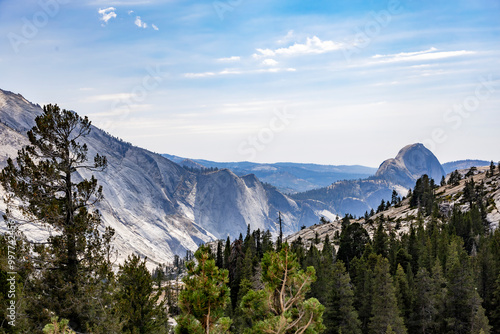 View from Olmsted Point in Yosemite National Park showcasing the majestic granite peaks, including Half Dome, with a rugged forest below and clear skies above. photo