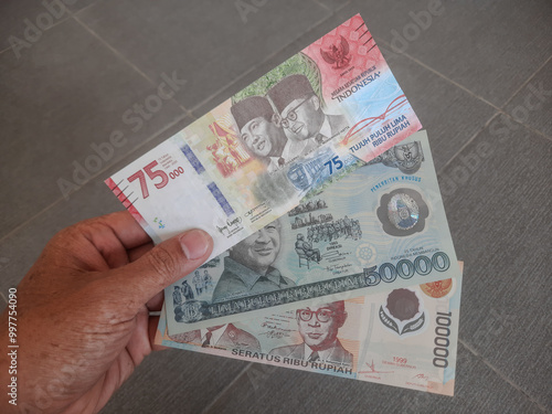 Three types of special edition Indonesian rupiah banknotes with denominations of seventy-five thousand, fifty thousand, and one hundred thousand.  photo