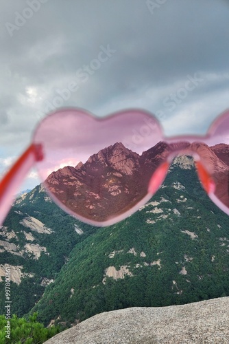 Rose-Colored Sunglasses in the shape of a heart close-up with mountains in the background. concept of love for mountains. Nature viewed through glasses