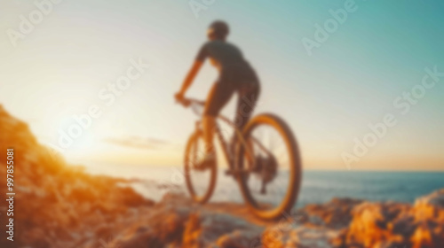 Blurred Silhouette of a Cyclist Ascending a Mountain Trail in the Sunrise Light