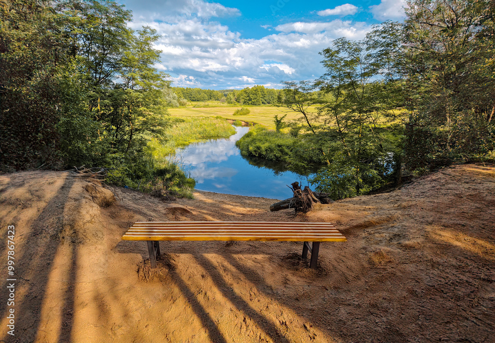 Fototapeta premium Small river flowing among fields, forests and its infrastructure.