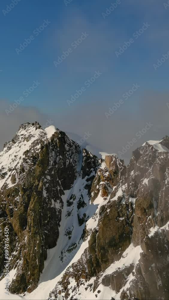 Clouds engulf a valley below snow capped mountain peaks and blue sky. British Columbia, Canada. Clouds engulf a valley below snow capped mountain peaks and blue sky. British Columbia, Canada.