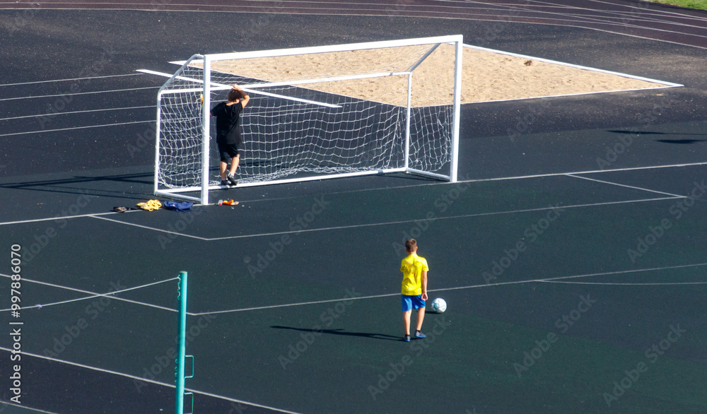 Obraz premium A boy in a yellow shirt is playing soccer on a field