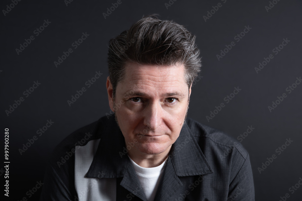 Close-up portrait of a very serious and sad 50-year-old man looking at camera. Dark background. Copy space. Concept of sadness, depression and mental health Close-up portrait of a very serious and sad 50-year-old man looking at camera. Dark background. Copy space. Concept of sadness, depression and mental health