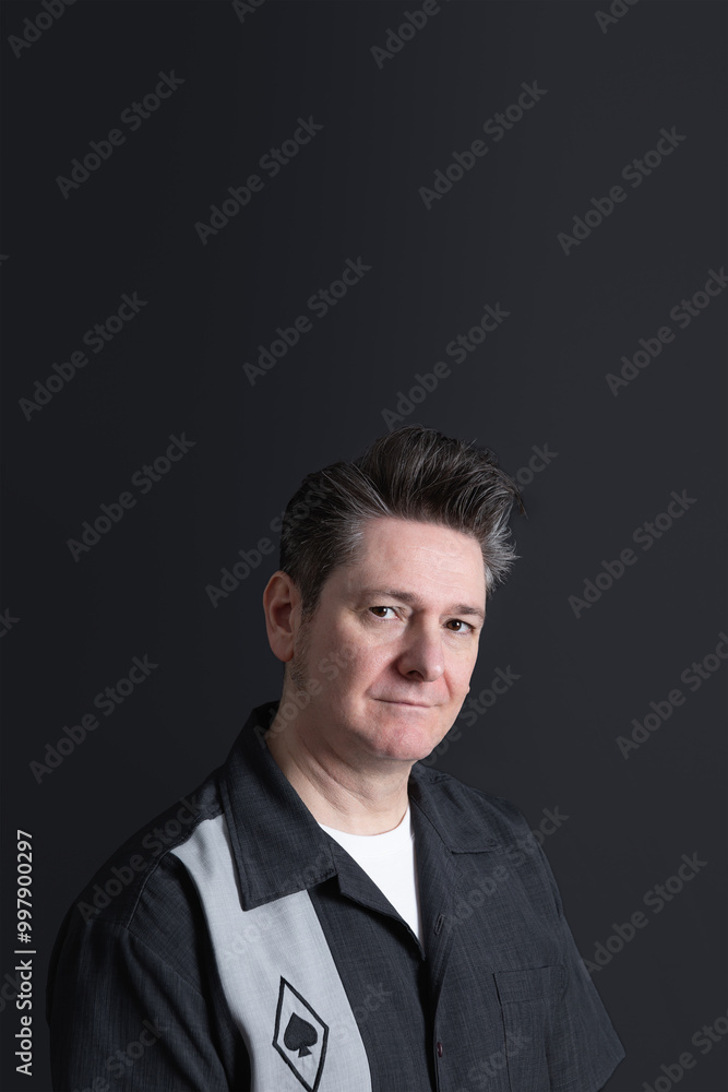 Portrait of a 50 years old man looking at camera smiling with calm and confident look. Dark background. Copy space. Concept of men and maturity Portrait of a 50 years old man looking at camera smiling with calm and confident look. Dark background. Copy space. Concept of men and maturity