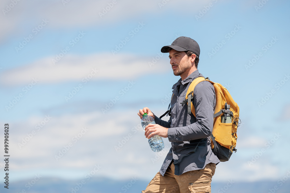 Young man enjoying nature. Drinking water is very important and healthy. Always stay hydrated. Hiking in the mountains, observing the landscape. Practicing sports and physical activity. Moments Young man enjoying nature. Drinking water is very important and healthy. Always stay hydrated. Hiking in the mountains, observing the landscape. Practicing sports and physical activity. Moments