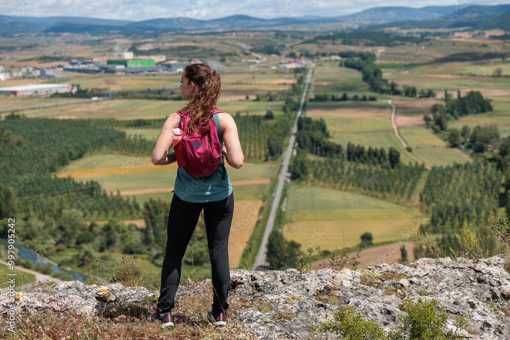 Naklejka premium Young woman enjoying nature.Hiking in the mountains, observing the landscape.Doing sports and physical activity.Let's take care of our natural surroundings and our environment.Moments of disconnection