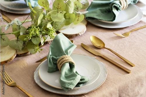 Elegant Festive table setting, white plates, gold cutlery, green napkin and centrepiece . Tableware for Christmas, Thanksgiving festive setting
