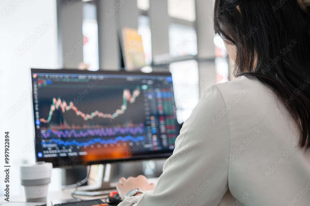 Young woman examines stock graphs at office desk