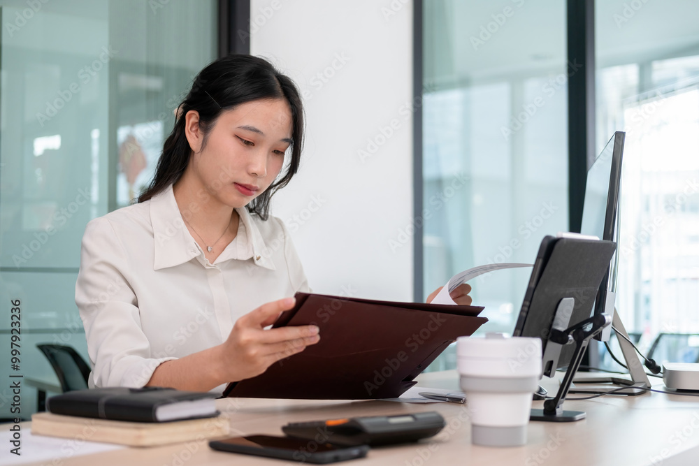 Young woman examines stock graphs and files at office desk Young woman examines stock graphs and files at office desk