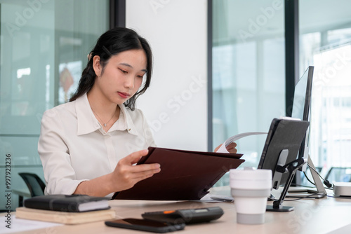 Young woman examines stock graphs and files at office desk