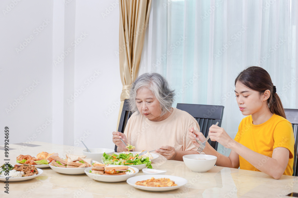 Mother and adult daughter eating meal together, Senior woman and daughter having breakfast in morning together Mother and adult daughter eating meal together, Senior woman and daughter having breakfast in morning together