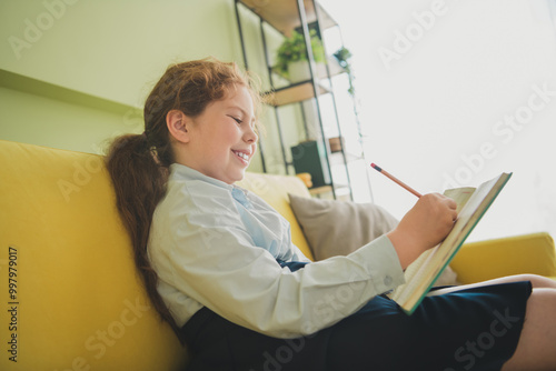 Photo of charming clever nice girl learner sitting couch doing hometask study from home daylight indoors photo