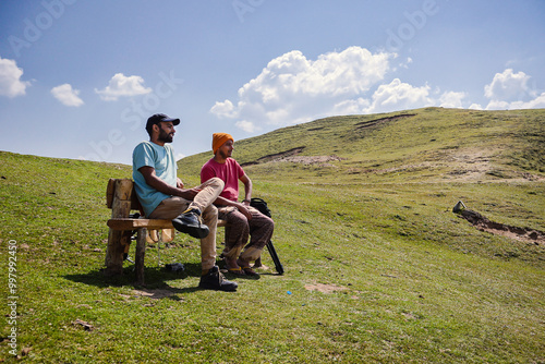 Two men sitting on a bench  at the Top of Raghupur Fort - Tirthan Valley himanchal pradesh india. photo