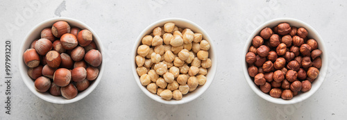 Bowls with whole and peeled and blanched healthy hazelnut nuts on light background.Top view.